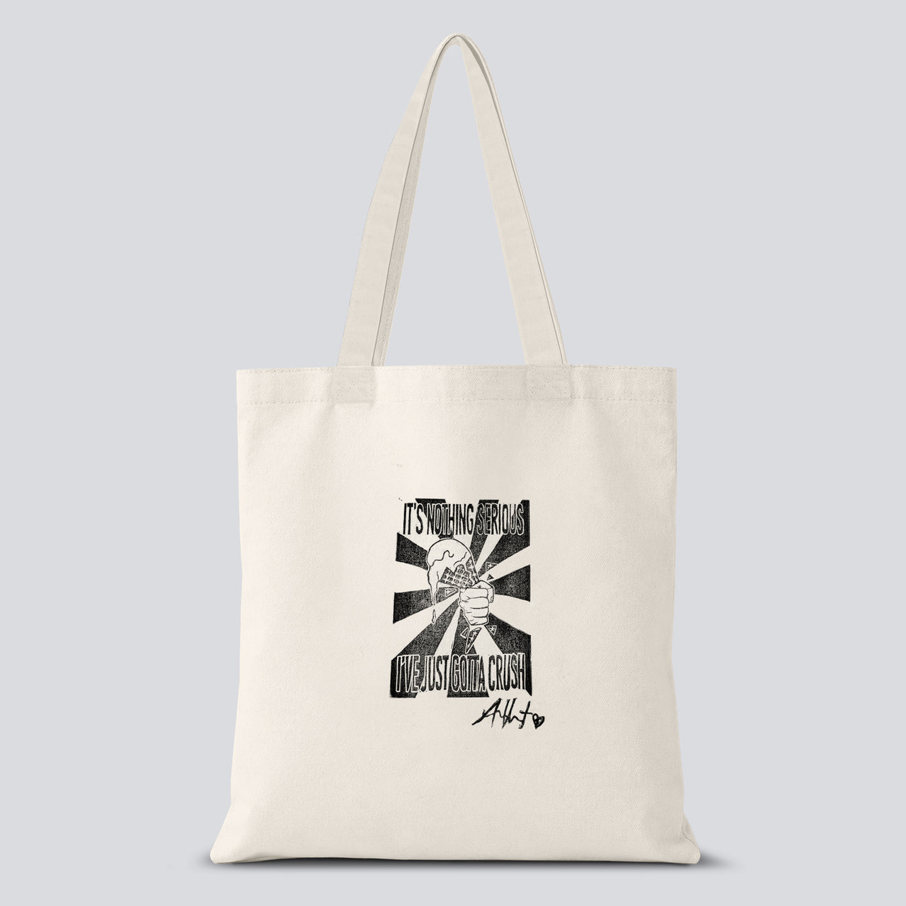 White tote bag with a hand crafted stamp design of a hand crushing an ice cream cone with text saying "It's nothing serious I've just gotta crush" on it