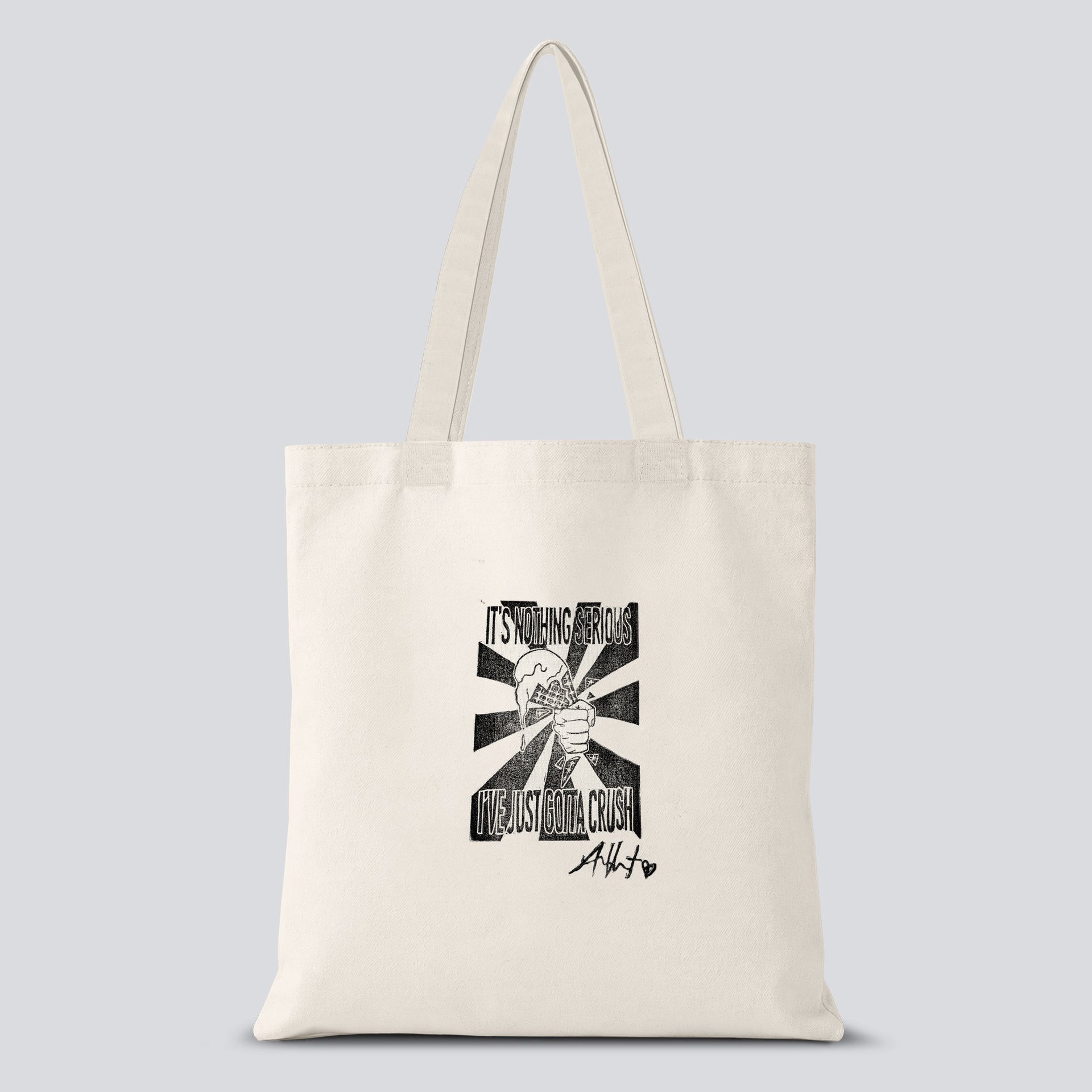White tote bag with a hand crafted stamp design of a hand crushing an ice cream cone with text saying "It's nothing serious I've just gotta crush" on it
