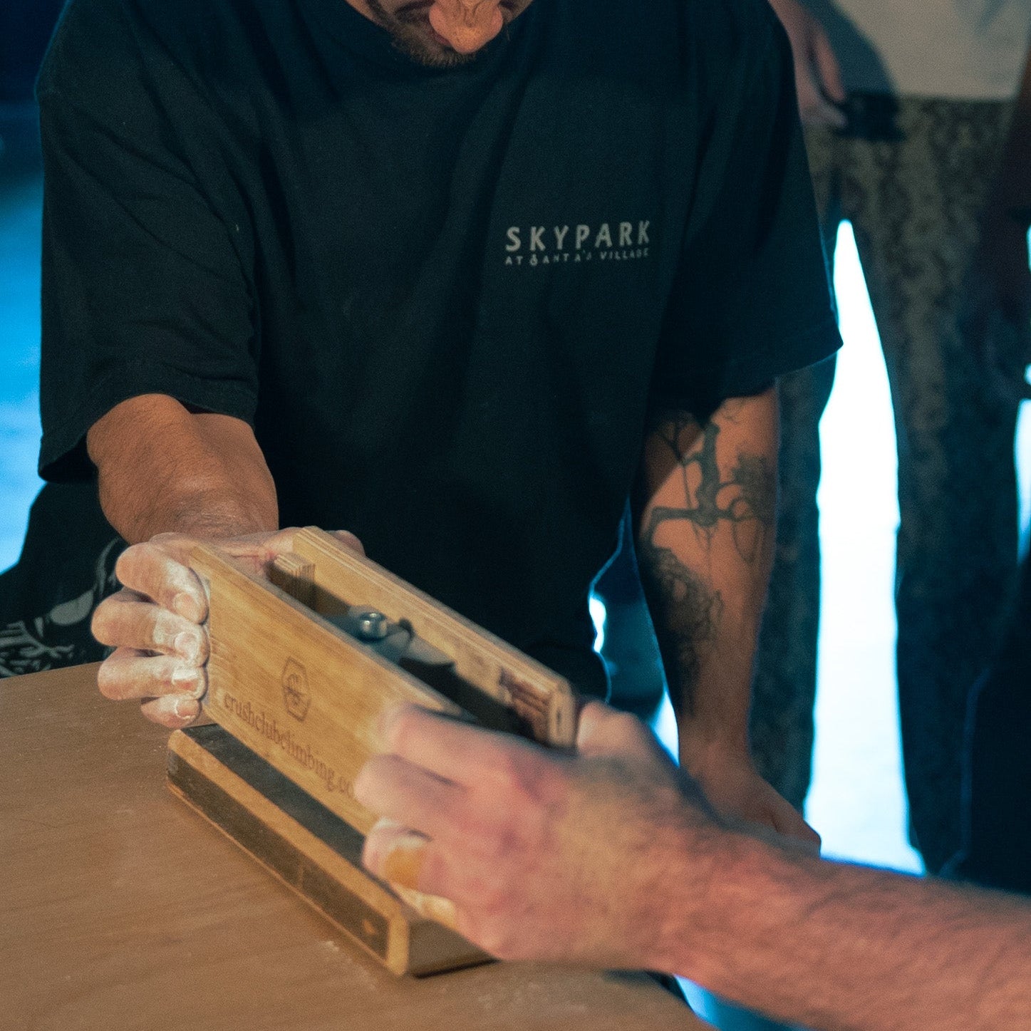 2 people pinching a wooden see saw