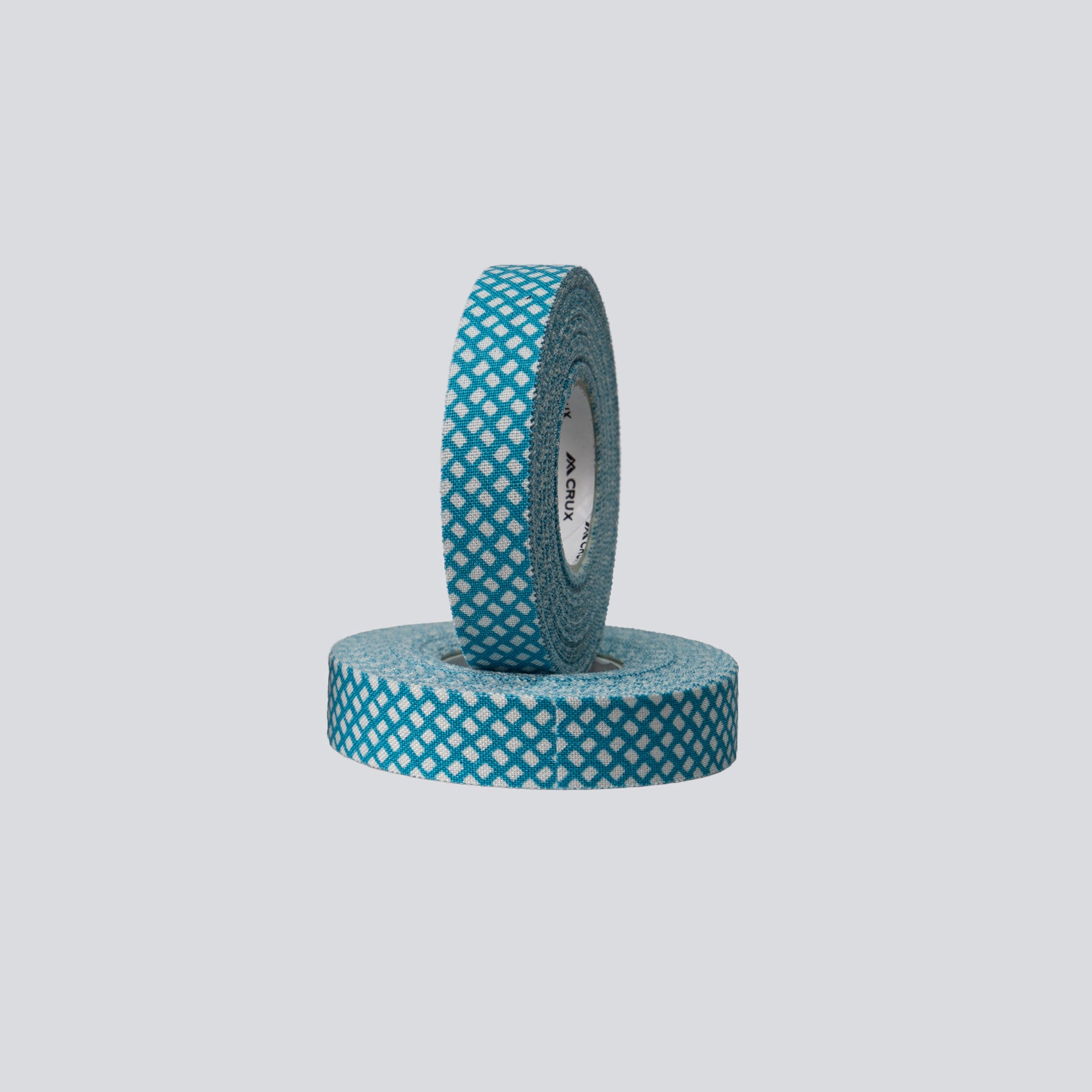 Two rolls of teal tape with white pattern on a light gray background