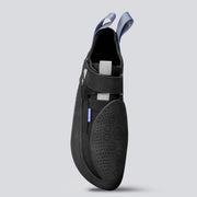 Top down view of a black climbing shoe with gray and blue accents on a light gray background