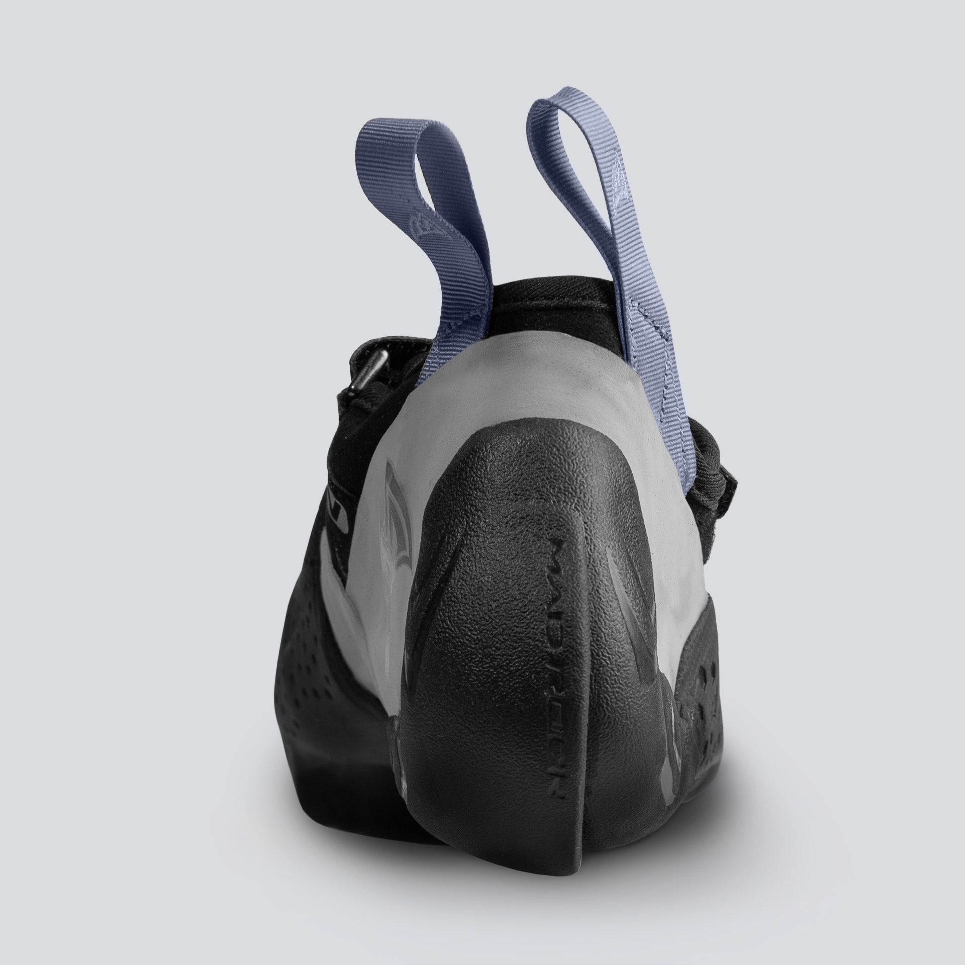 The heel of a black climbing shoe with gray and blue accents on a light gray background
