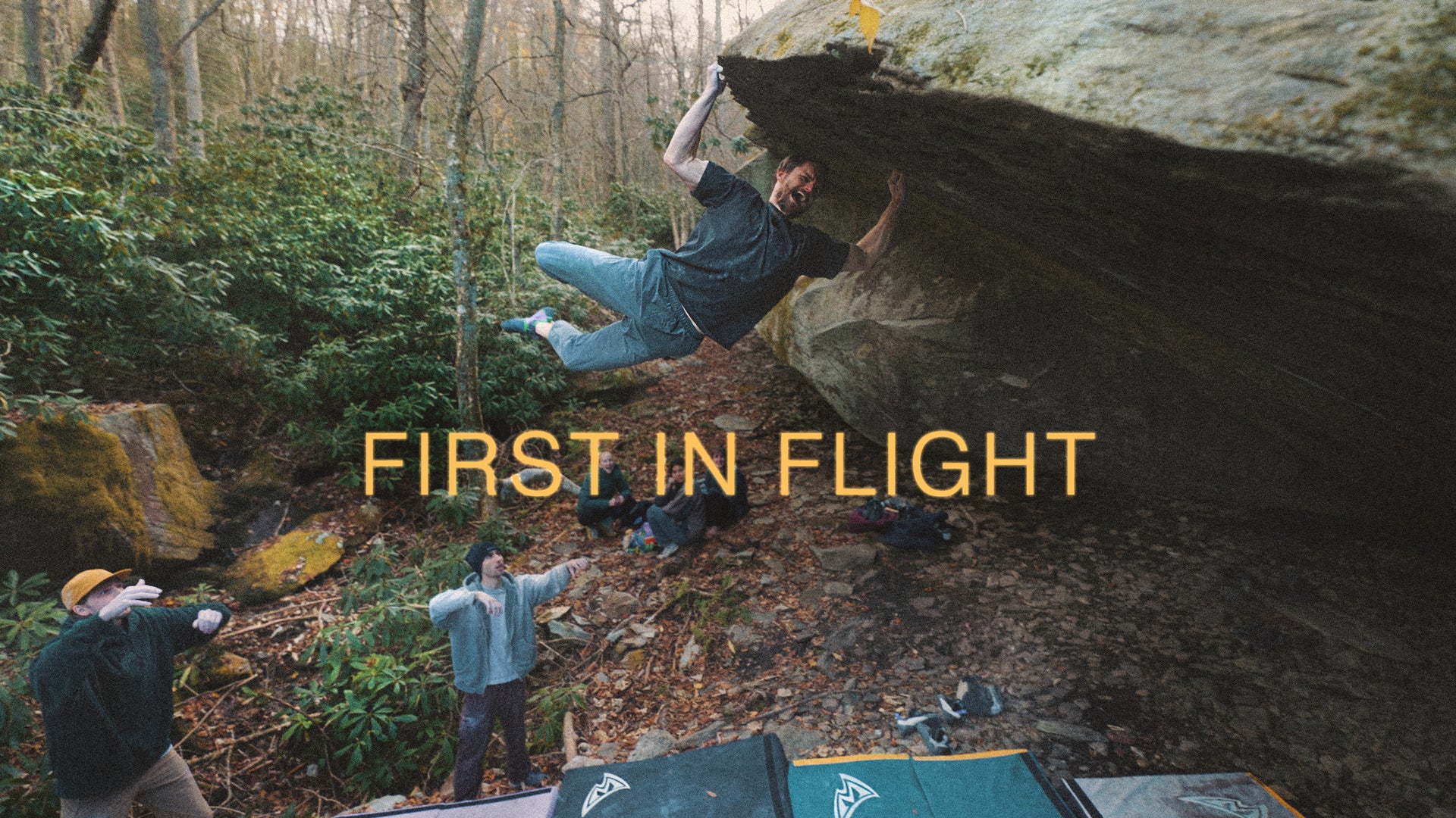Person bouldering on a rock with 'First in Flight' text overlay in a forest setting