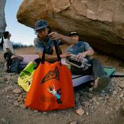 3 climbers sitting near a rock with tote bags in the foreground