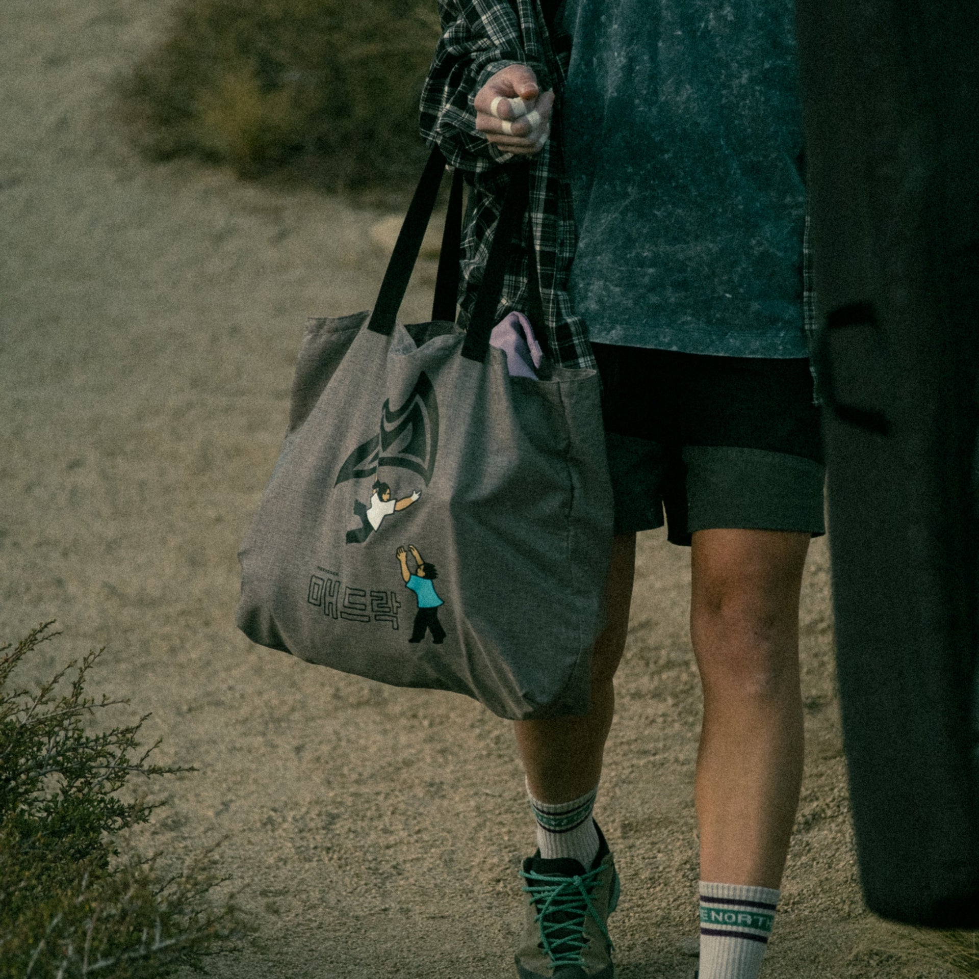 a climber carrying a tote bag on a dirt path