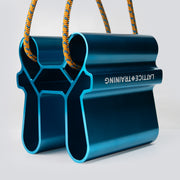 A blue metallic pinch training tool with an orange cord running through it