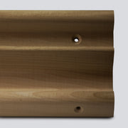 A close up of a wooden hangboard with 3 different edges on a grey background