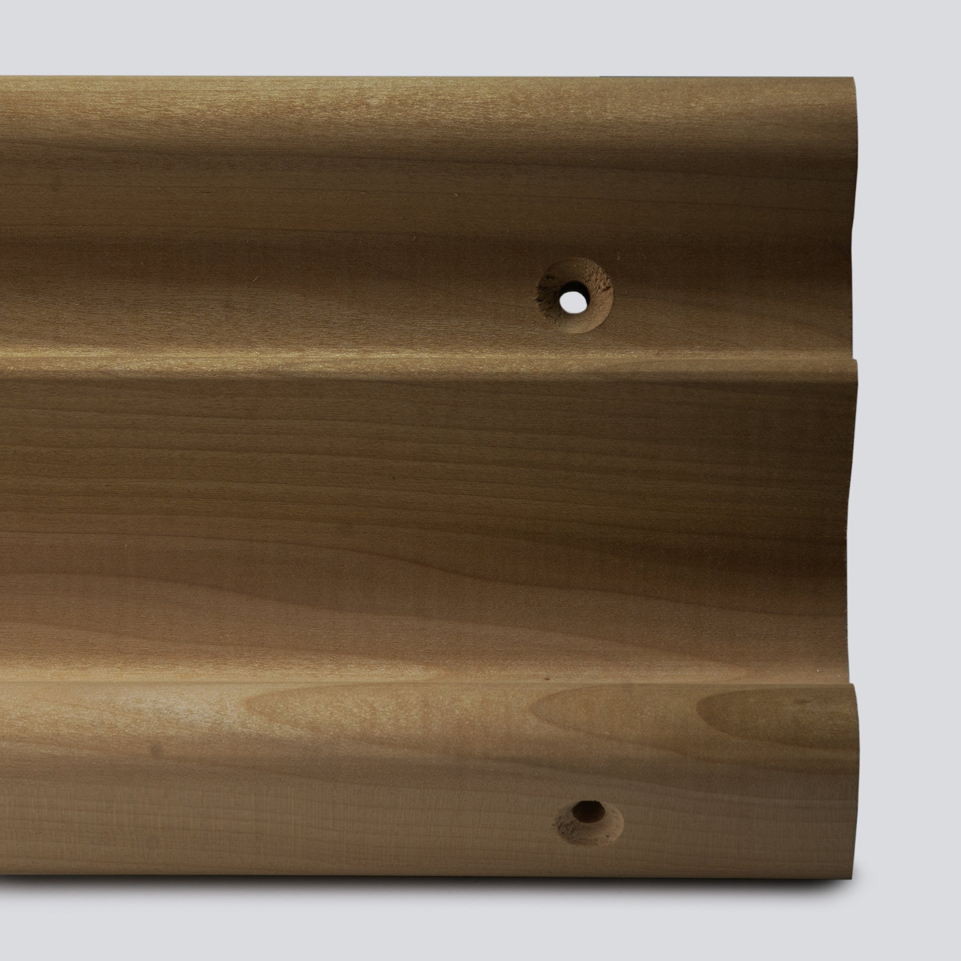 A close up of a wooden hangboard with 3 different edges on a grey background