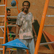 athlete Mickael Mawem wearing an acid wash shirt, smiling while holding a large climbing hold in his hand