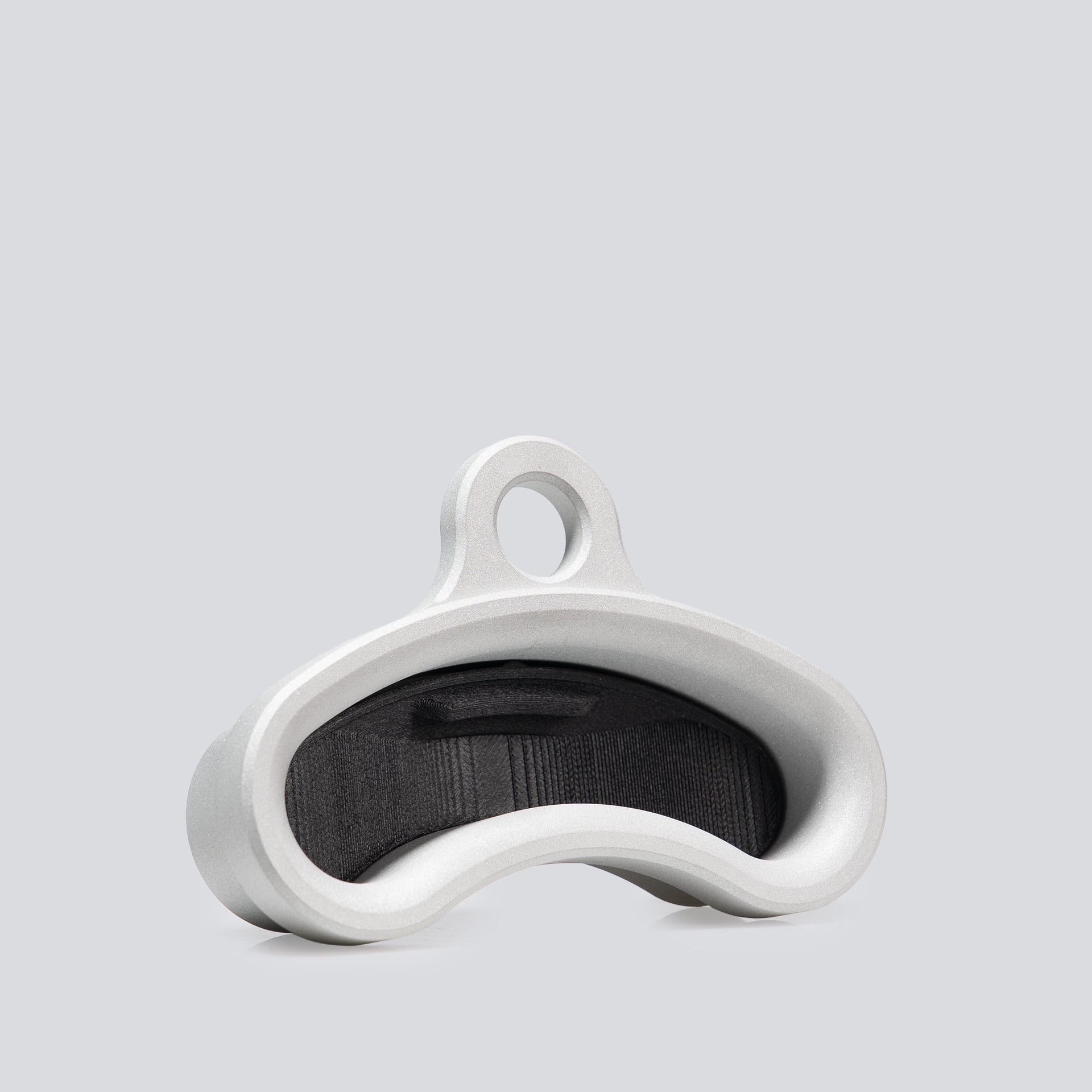 An isometric view of an aluminum finger training tool that has an ergonomic curved shape and an insert inside of it to change the edge depth.